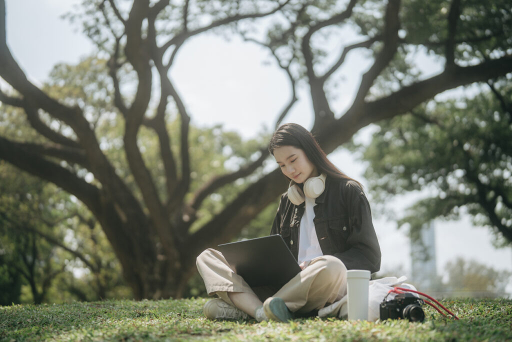 A woman working on her computer from a park.