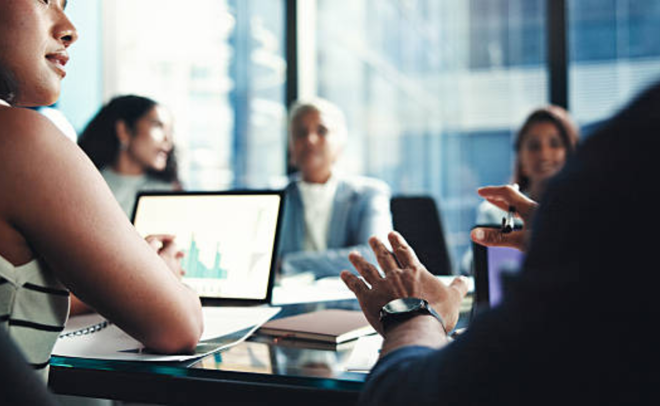 people in a meeting with a laptop open at a table